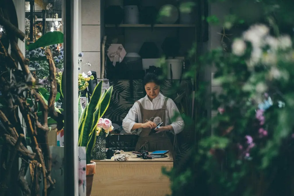 Une fleuriste dans son atelier entourée de plantes